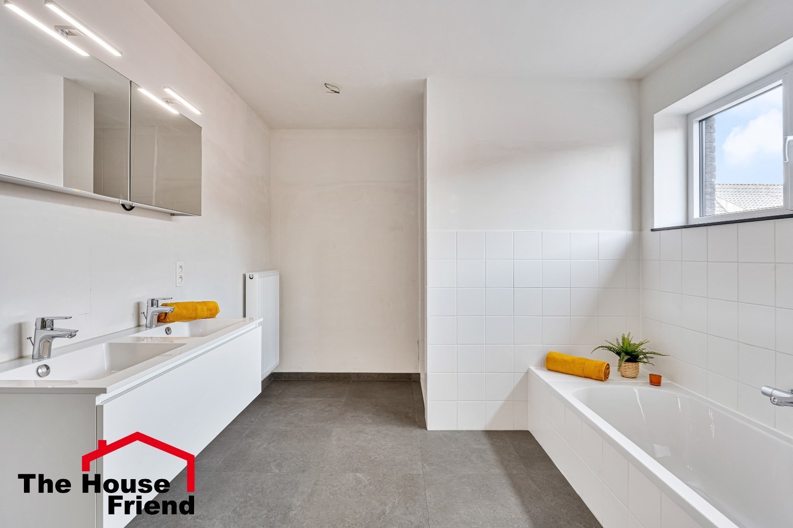 Badkamer met dubbele lavabo's, ligbad, inloopdouche en hangtoilet 