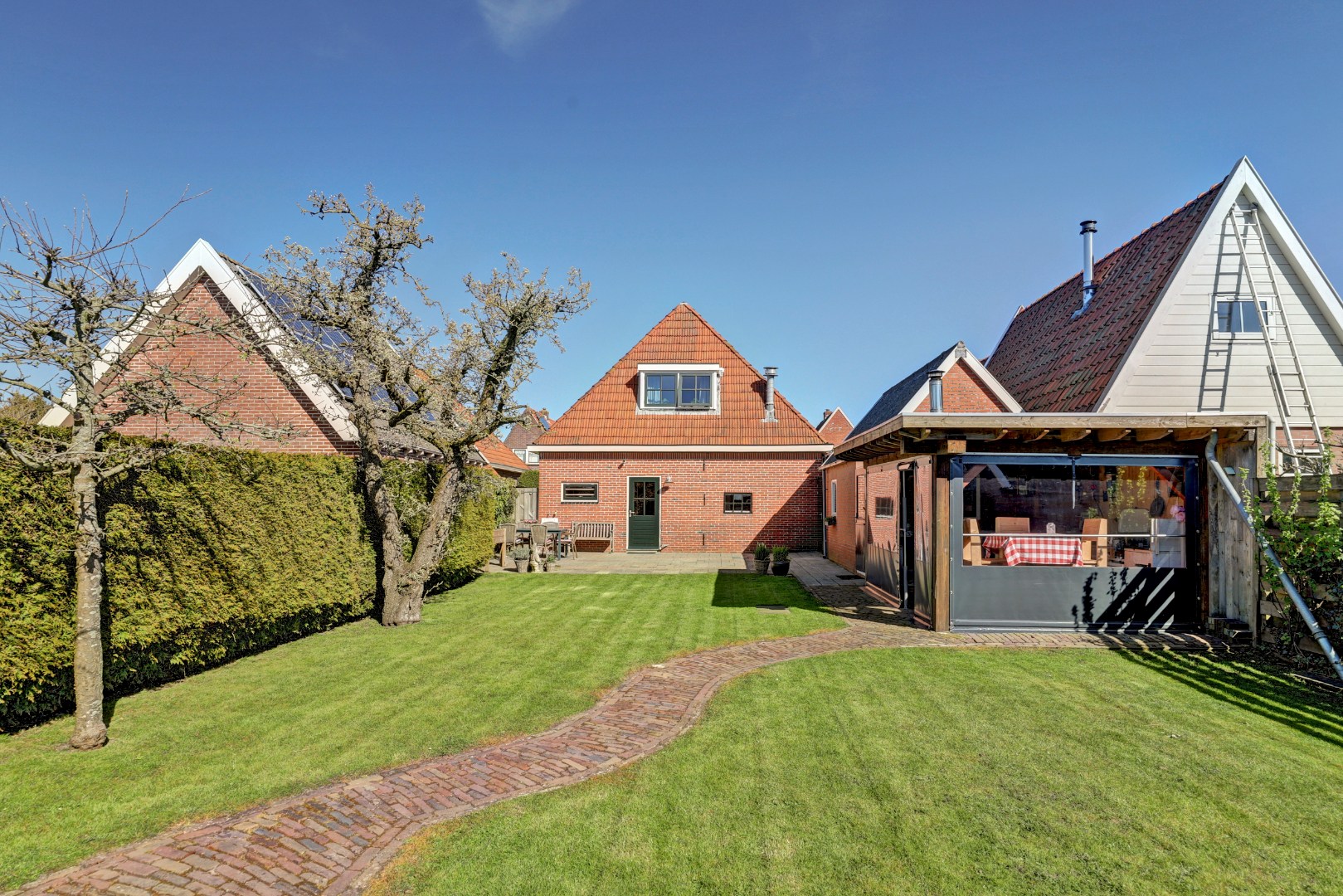 Vrijstaande woning met diepe zonnige tuin, overkapping en royale bijgebouwen 