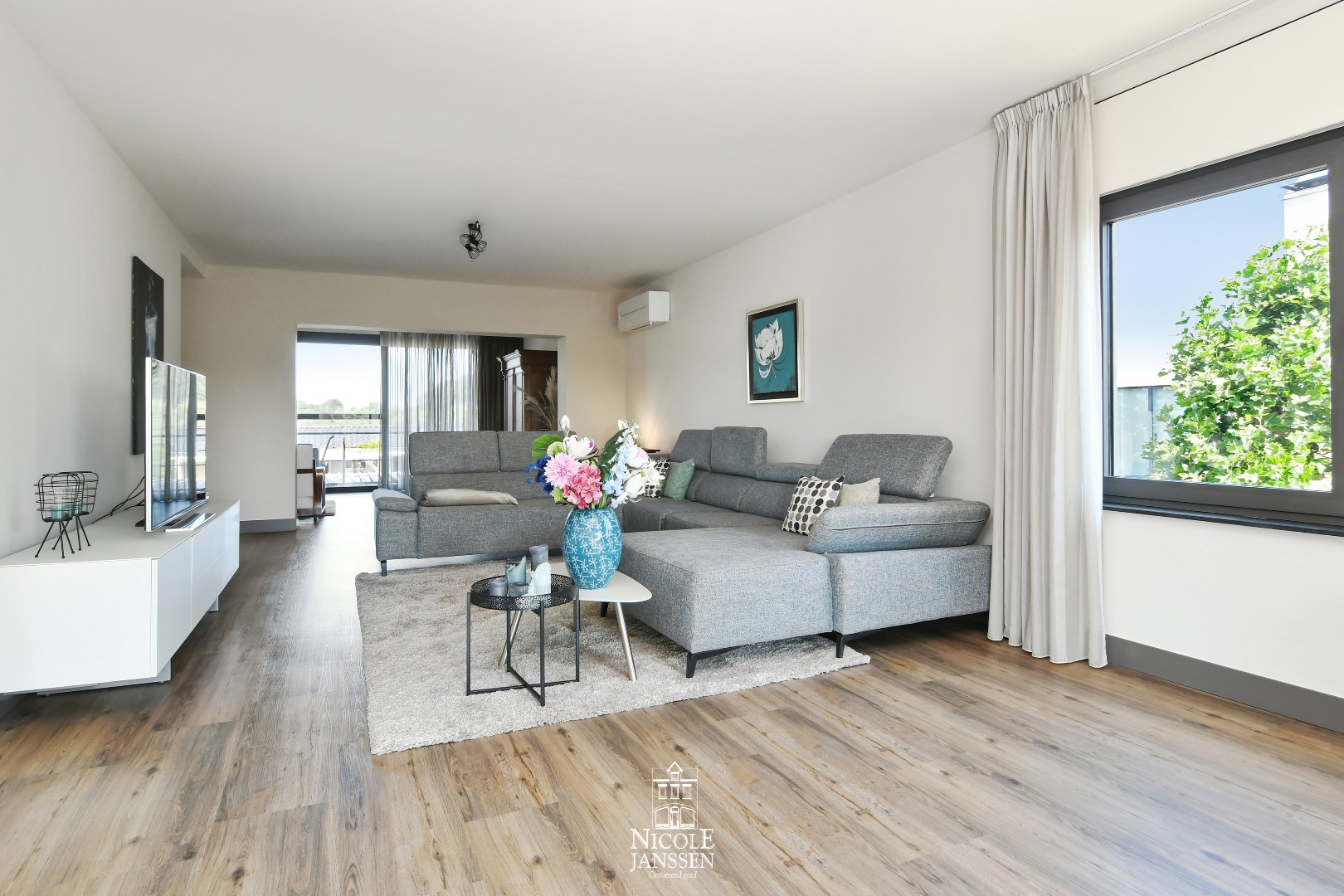 Gezellige open leefruimte met veel natuurlijk lichtinval door de grote raampartijen 