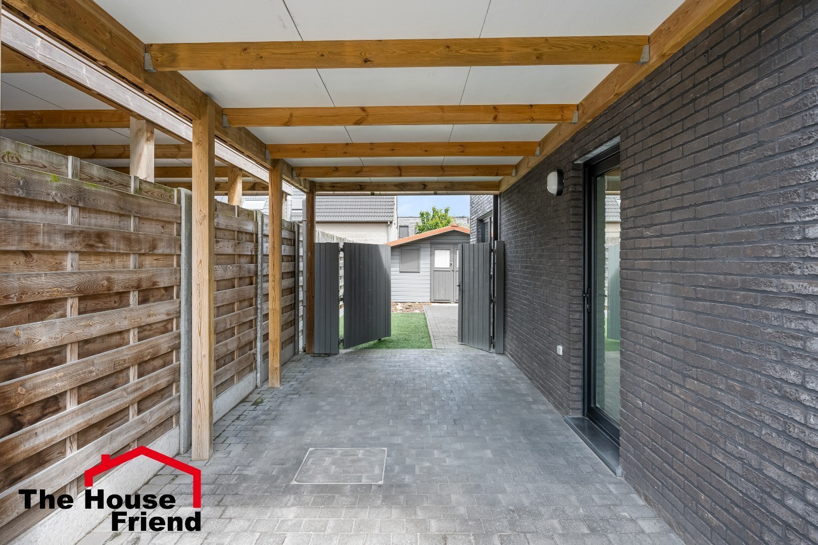 Carport met hekwerk naar de tuin. 