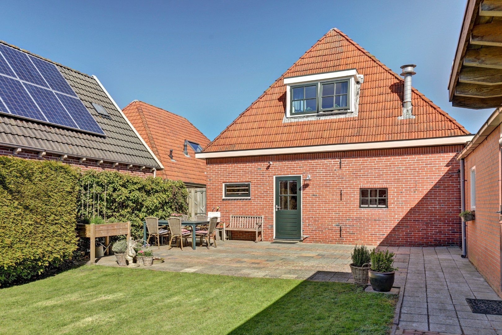 Vrijstaande woning met diepe zonnige tuin, overkapping en royale bijgebouwen 