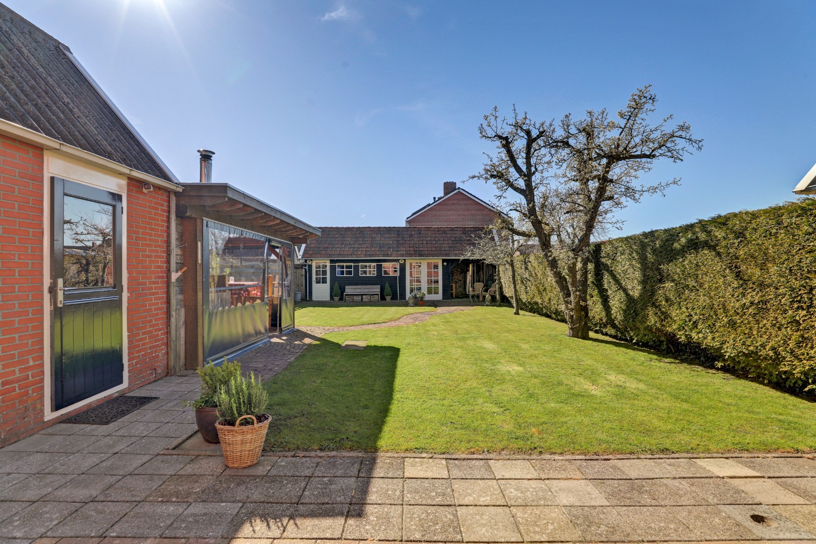 Vrijstaande woning met diepe zonnige tuin, overkapping en royale bijgebouwen 