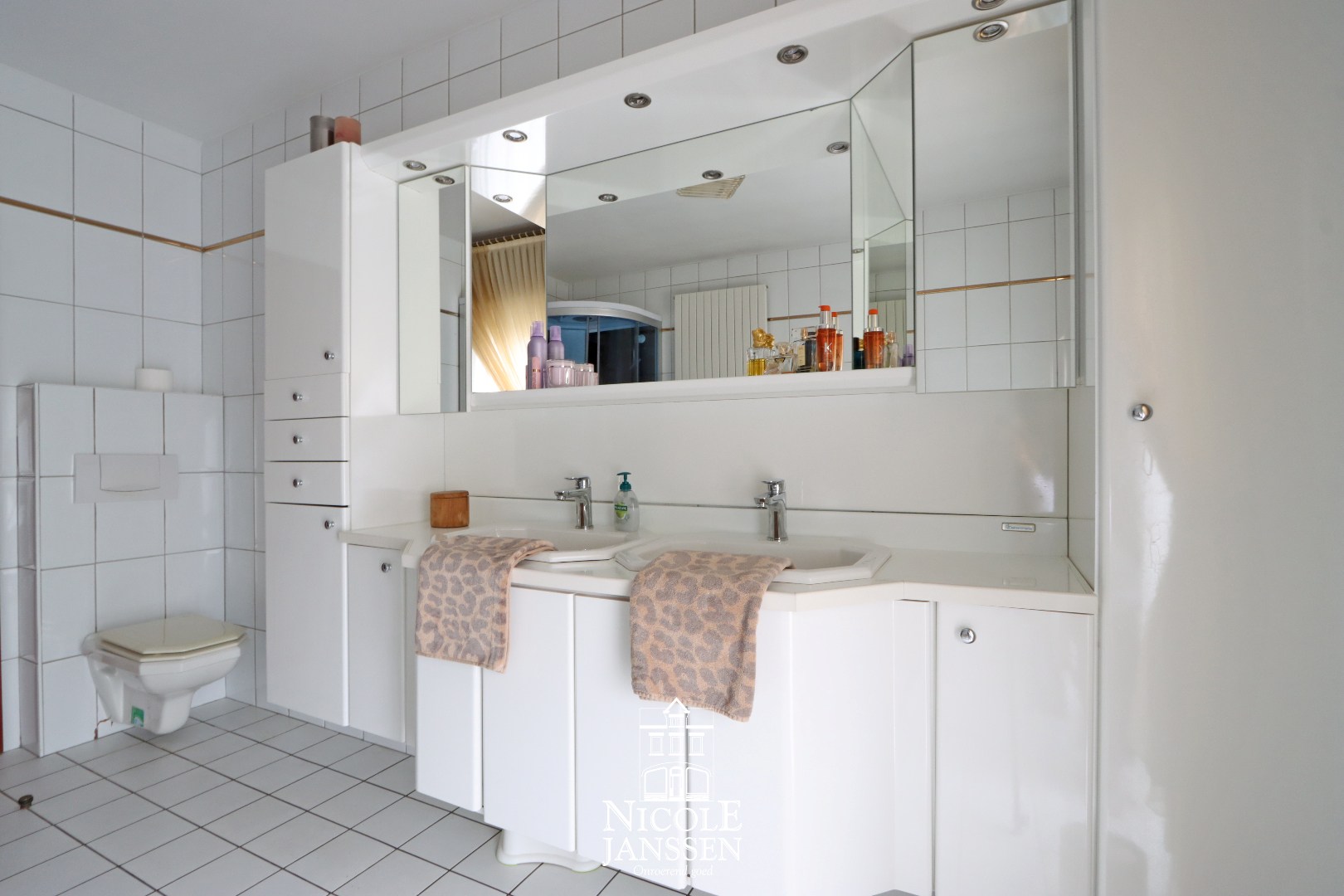 Badkamer met ligbad, douche, dubbele lavabo en toilet