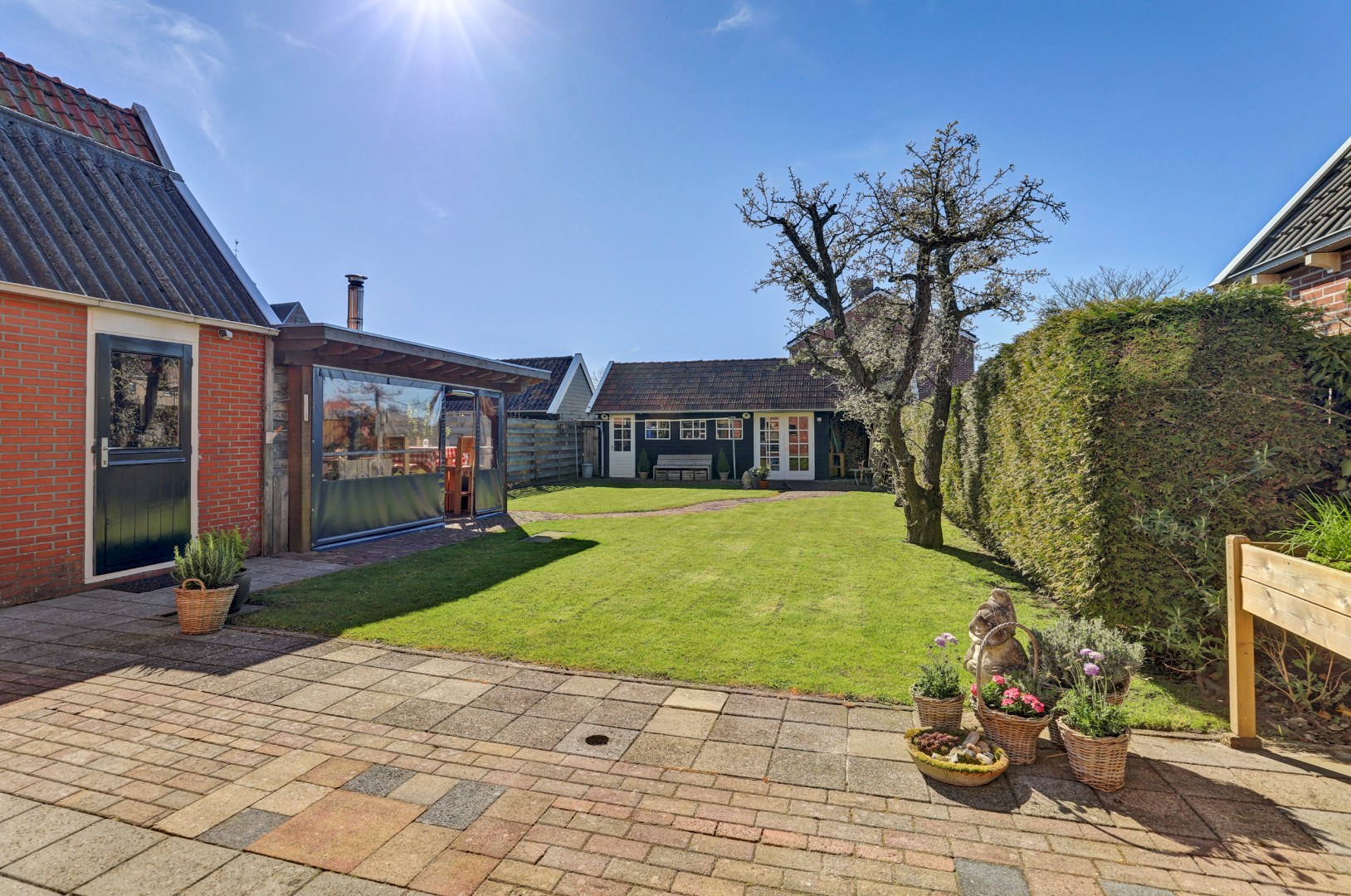 Vrijstaande woning met diepe zonnige tuin, overkapping en royale bijgebouwen 