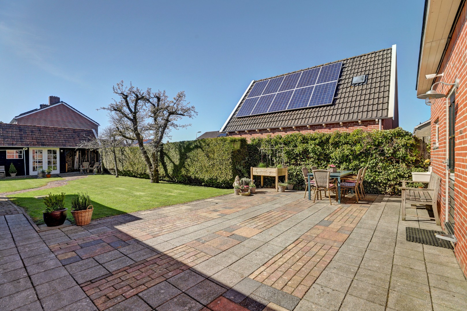 Vrijstaande woning met diepe zonnige tuin, overkapping en royale bijgebouwen 